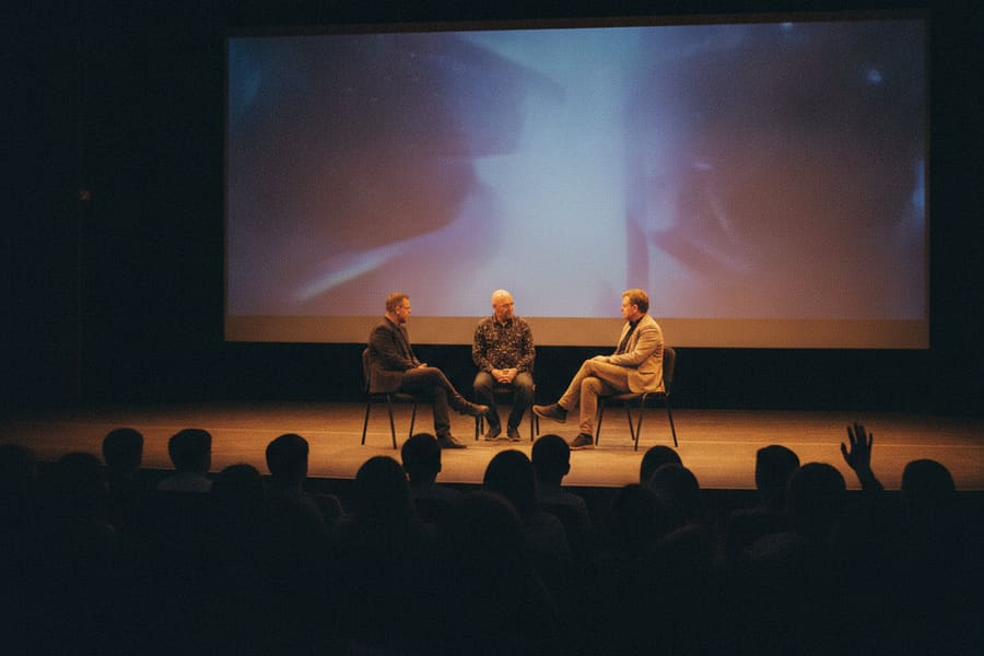 Ett samtal på scenen efter en filmvisning, publiken sedd bakifrån och en hand i luften